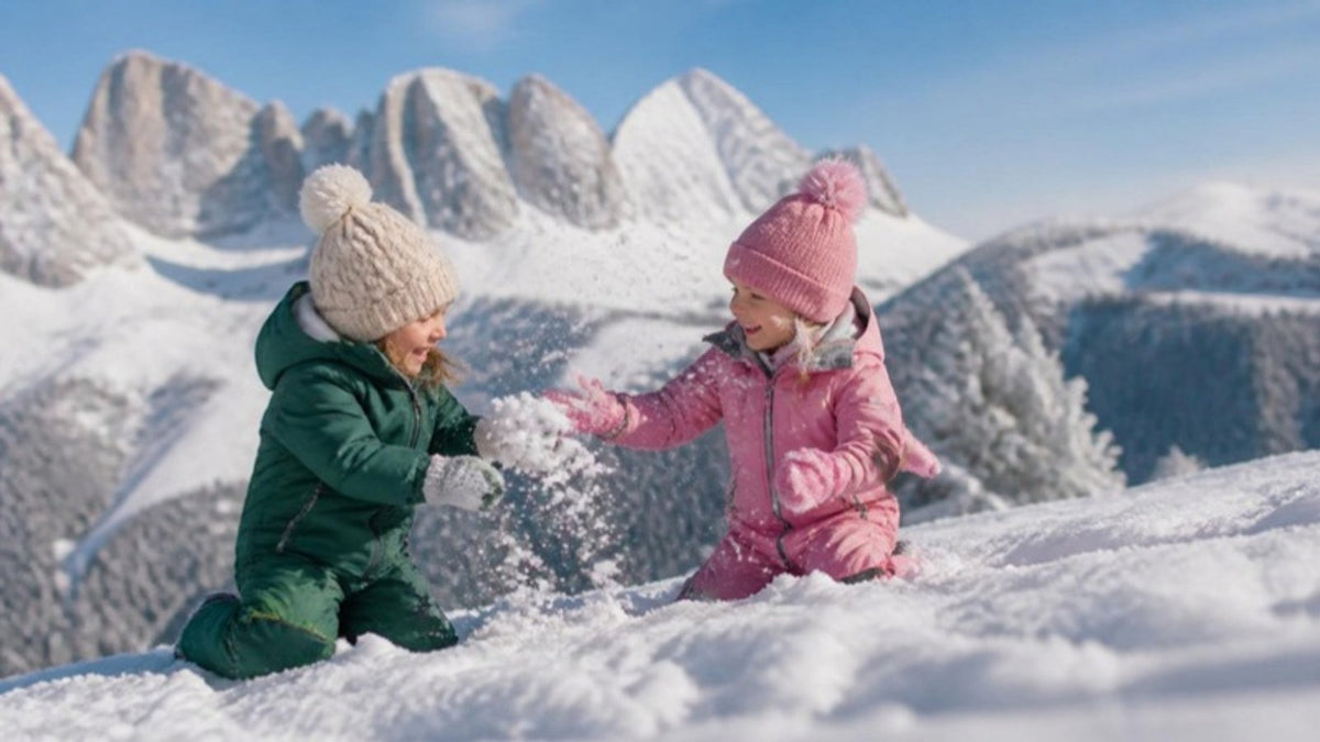 Due bambini in tuta da neve giocano sulle Dolomiti